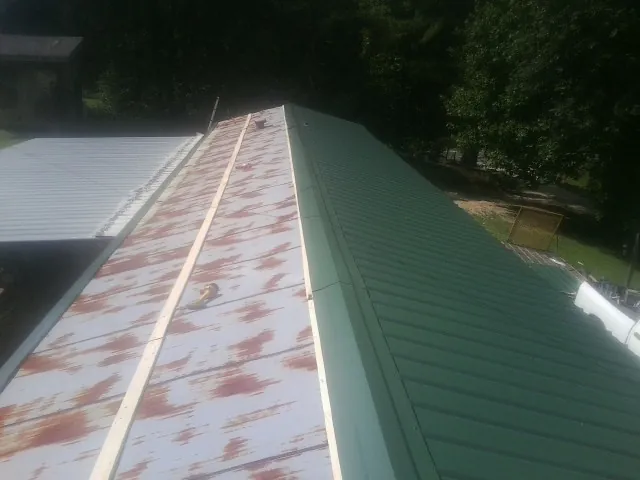Old rusted panels beside newly installed green metal roofing — Wind Damage Roof Repair by Roofing Brothers in Butte Falls
