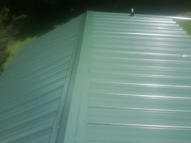 New green metal panels meeting at the ridge of a roof — Flat Roof Repair work by our crew in Butte Falls
