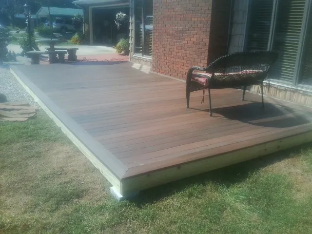 New wood deck and wicker chair beside a brick house in Butte Falls
