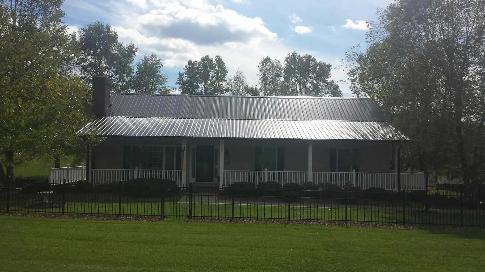 Gray metal roof on a brick ranch with a full width front porch — Gutter Guard Installation work by our crew in Butte Falls