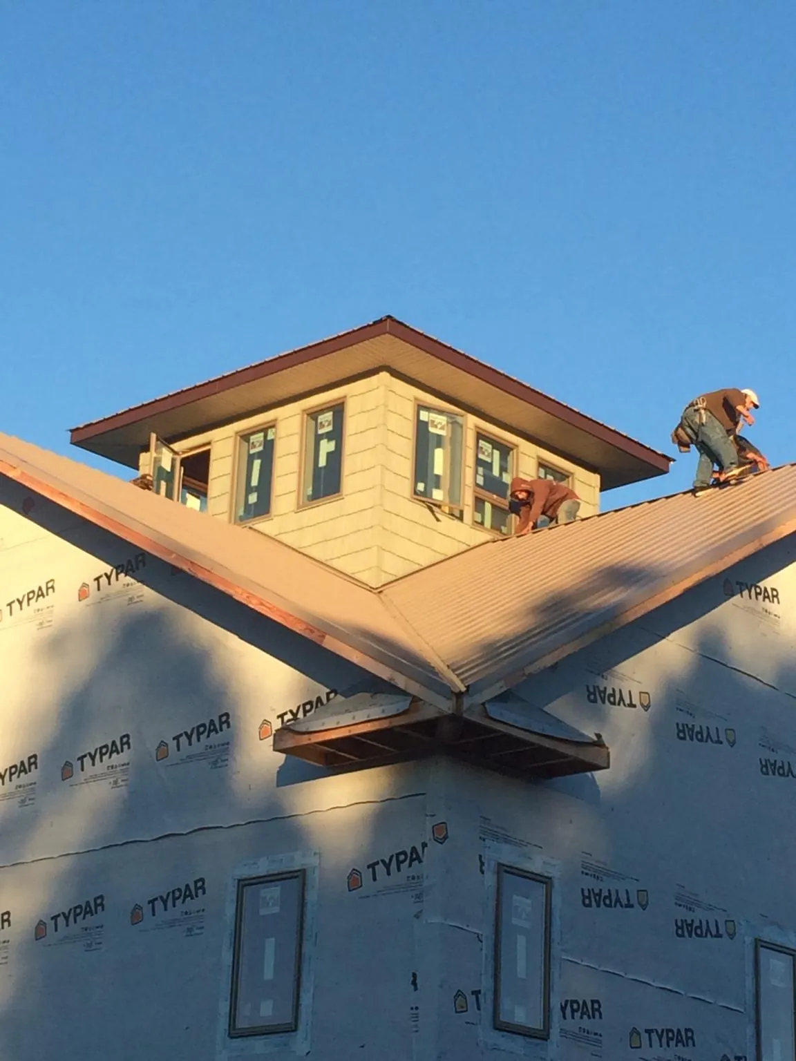 Roofers working around a rooftop cupola on a new metal roof at sunset — Roof Waterproofing in Butte Falls by Roofing Brothers